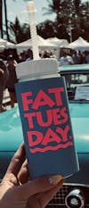 Fat Tuesday reusable cup held in front of a classic car
